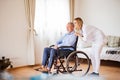 Nurse and senior man in wheelchair during home visit. Royalty Free Stock Photo