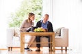 Health visitor and a senior man with tablet during home visit. Royalty Free Stock Photo