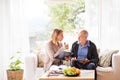 Health visitor and a senior man with tablet during home visit. Royalty Free Stock Photo