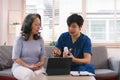 Health visitor and a senior woman with tablet during home visit. Elderly healthcare and Home health care service concept Royalty Free Stock Photo