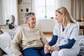 A health visitor talking to a sick senior woman sitting on bed at home. Royalty Free Stock Photo