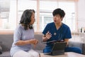 A health visitor is using a tablet to explain to a sick elderly woman how to take her pills.The visitor is taking Royalty Free Stock Photo