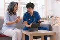 A health visitor is using a tablet to explain to a sick elderly woman how to take her pills.The visitor is taking Royalty Free Stock Photo