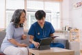 A health visitor is using a tablet to explain to a sick elderly woman how to take her pills.The visitor is taking Royalty Free Stock Photo