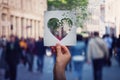 Health and wellbeing global issue as human hand holding a paper with heart symbol breaking into pieces over a crowded street Royalty Free Stock Photo