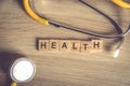 Health word background on wood blocks with yellow stethoscop on wood background , top view ,healthy concept