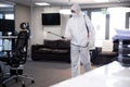 Health worker wearing protective clothes cleaning the office using disinfectant