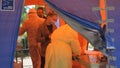 Health workers in suits of epidemiological protection check visitors at entrance to hospital. Abstract defocused image