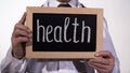 Health written on blackboard in doctor hands, healthcare reform presentation