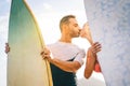Health young couple of surfers kissing at sunset on the beach holding surfboards - Happy lovers having a tender moment with a kiss Royalty Free Stock Photo