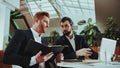 Office Managers in Suit Compare Data on Laptop