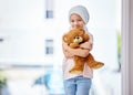 Healthcare, child and portrait of a cancer patient holding a teddy bear for support or comfort. Medical, smile and girl