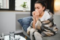 healthcare, cold, allergy and people concept - sick woman blowing her runny nose in paper tissue at home. Royalty Free Stock Photo