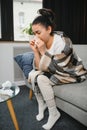 healthcare, cold, allergy and people concept - sick woman blowing her runny nose in paper tissue at home. Royalty Free Stock Photo