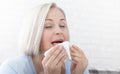 Healthcare, cold, allergy and people concept, sick woman blowing her runny nose in paper tissue on white background