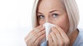 Healthcare, cold, allergy and people concept, sick woman blowing her runny nose in paper tissue on white background