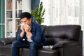 Healthcare concept, allergy and people concept - sick asian man blowing his runny nose in paper tissue sit on the sofa at home Royalty Free Stock Photo