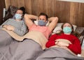 Sick family in protective masks lying in bed