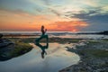 Young woman practicing Virabhadrasana I, Warrior I Pose. Hands in namaste mudra. Amazing water reflection. Tanah Lot temple, Bali Royalty Free Stock Photo