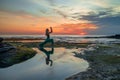 Young woman practicing Virabhadrasana I, Warrior I Pose. Hands in namaste mudra. Amazing water reflection. Tanah Lot temple, Bali Royalty Free Stock Photo