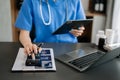 Healthcare costs and fees concept.Hand of smart doctor used a calculator and smartphone, tablet for medical costs at hospital in Royalty Free Stock Photo