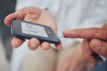 Healthcare, diabetes and senior man with glucometer checking blood sugar level on finger closeup. Health, innovation and Royalty Free Stock Photo