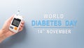 Healthcare and medical concept, Top view hand holding blood glucose meter test on pastel blue background. World Diabetes day, 14