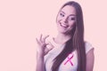 Woman pink cancer ribbon on chest making ok sign