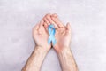 Healthcare and medicine concept - blue ribbon of prostate cancer awareness in male hands, achalasia and adrenocortical cancer, on