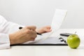 Healthcare and medicine concept - doctor with medical clipboard, green apple analyzing cardiogram.