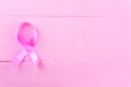 Healthcare, medicine concept. Pink breast cancer awareness ribbon on pink wooden background with copy space for text. Flat lay, Royalty Free Stock Photo