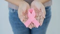 Healthcare and medicine concept - womans hands holding pink breast cancer awareness ribbon on white background Royalty Free Stock Photo