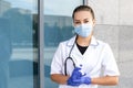 European female doctor with a stethoscope wearing a white coat, rubber gloves, and a protective mask and holding a syringe in hand Royalty Free Stock Photo