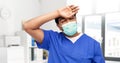 tired indian male doctor in blue uniform and mask