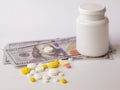 Healthcare savings and expencive medicine concept. Pills scattered over dollar banknotes. Bottle of pills and money Royalty Free Stock Photo