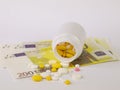 Healthcare savings and expencive medicine concept. Pills scattered over euro banknotes. Bottle of pills and money Royalty Free Stock Photo