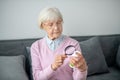 Senior woman with magnifier scrutinizing the medicines