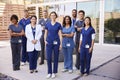 Healthcare team with ID badges stand outdoors, full length