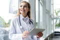 Healthcare, technology and medicine concept - smiling female doctor with stethoscope taking notes at tablet pc computer. Royalty Free Stock Photo