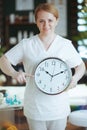happy massage therapist woman in spa salon with clock