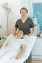 happy massage therapist woman in massage cabinet with client