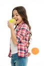 Healthcare tricks. Kid girl cunning eats apple while holds lollipop behind back. Whom she tries to trick. Girl pretend Royalty Free Stock Photo