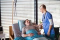 Healthcare worker or nurse tallking to senior patient in bed in hospital. Royalty Free Stock Photo