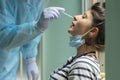 Healthcare worker with protective equipment performs coronavirus swab on Caucasian girl