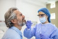 Healthcare worker with protective equipment performs coronavirus swab on elderly man. Nose swab for Covid-19 Royalty Free Stock Photo