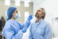 Healthcare worker with protective equipment performs coronavirus swab on elderly man. Nose swab for Covid-19 Royalty Free Stock Photo