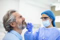 Healthcare worker with protective equipment performs coronavirus swab on elderly man. Nose swab for Covid-19 Royalty Free Stock Photo