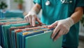 Healthcare worker sorts patient files. Person in teal uniform organizes colorful medical records. Efficient data retrieval