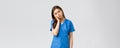 Healthcare workers, prevent virus and medicine concept. Tired sleepy female doctor, young nurse in blue scrubs, lean on Royalty Free Stock Photo