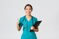 Healthcare workers, preventing virus, quarantine campaign concept. Smiling pretty asian doctor, female intern in scrubs Royalty Free Stock Photo